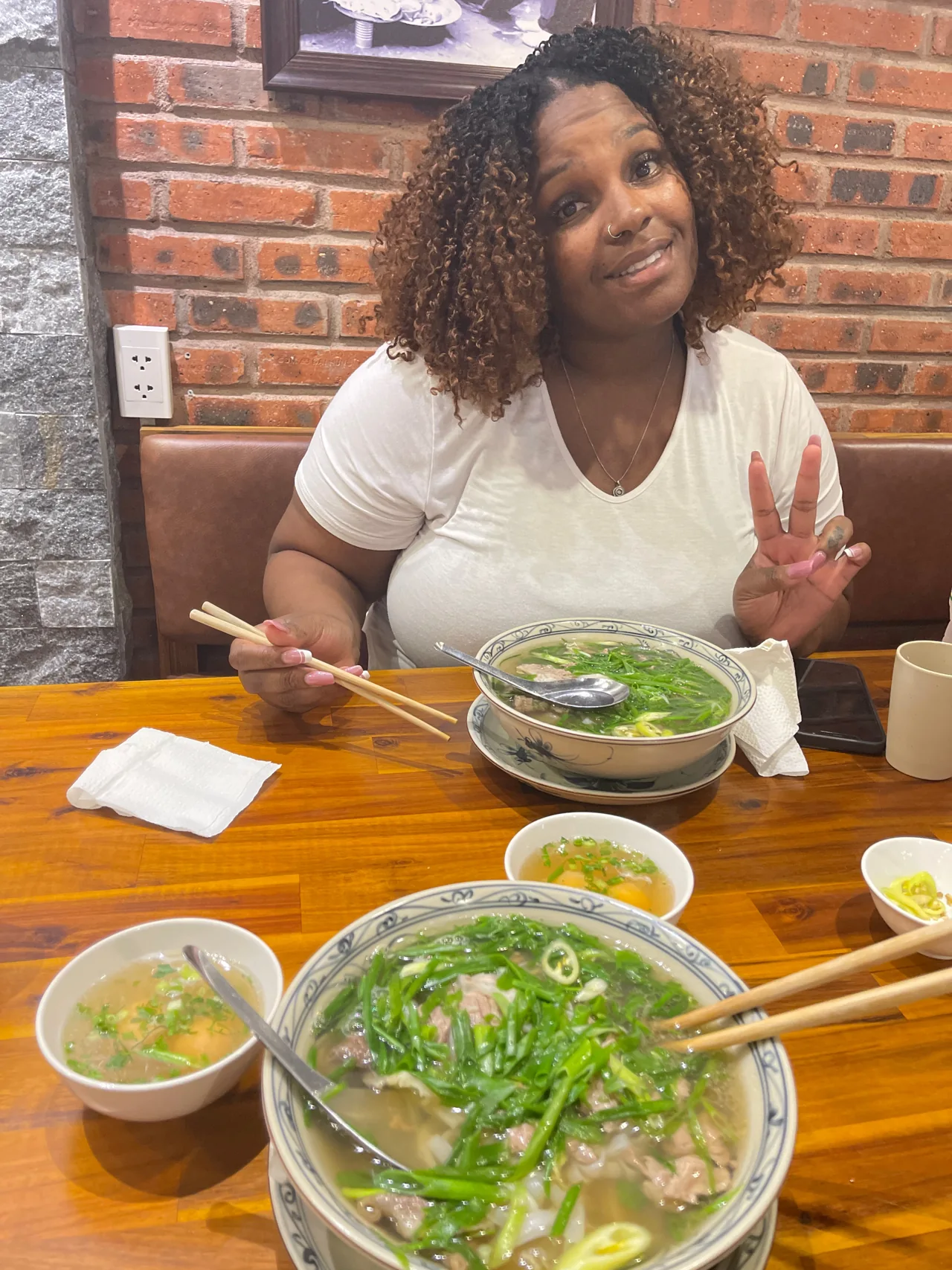 Amia smiling at a café with a bowl of pho